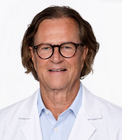 Dr. med. Wilhelm Knarr, ein Mann in weißem Arztkittel in hellen Praxisräumen